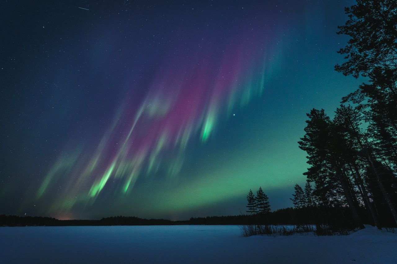 Northern lights illuminate the night sky over a serene lake in Oulu, Finland.