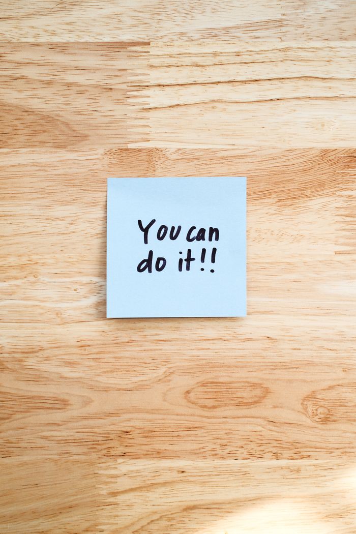 Crafting Captivating Headlines: Your awesome post title goes here A motivational message on a Post-It note placed on a wooden table.