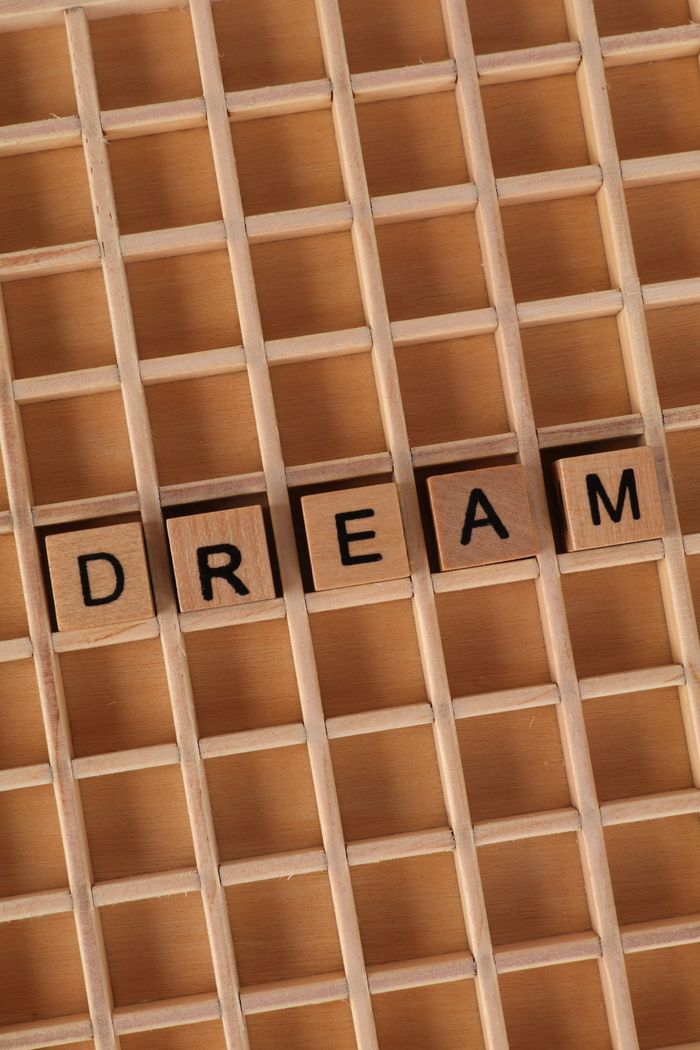 Close-up of wooden letter tiles spelling 'Dream' on a grid background. Perfect for motivation and inspiration themes.