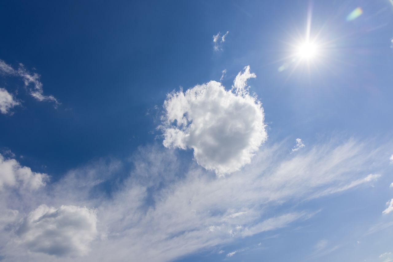 Crisp blue sky with bright sunlight and scattered white clouds on a clear day.